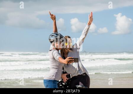 Due donne scattano una foto selfie al mare a Costa da Caparica, Almada, Portogallo Foto Stock