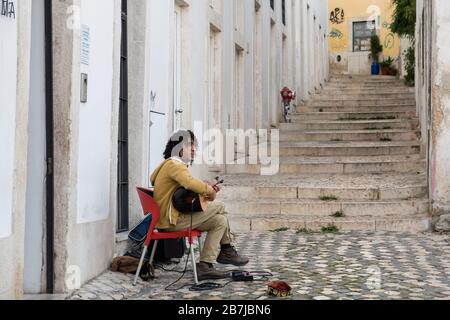Musicista di strada nel distretto di Alfama, suonando la tradizionale chitarra fado portoghese, Lisbona, Portogallo Foto Stock