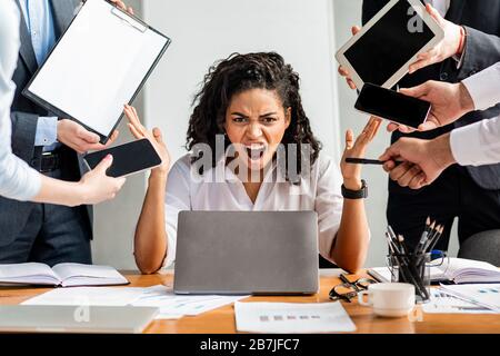Una donna fidata al laptop che urla furiosamente seduto in ufficio Foto Stock