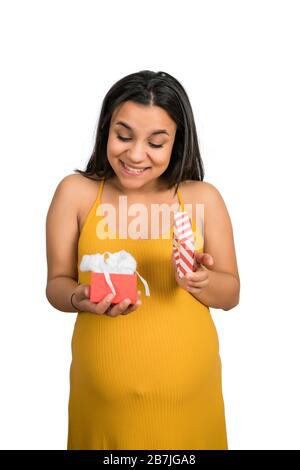 Primo piano della donna incinta che tiene e apre la confezione regalo su sfondo bianco. Gravidanza, nuova mamma e concetto di maternità. Foto Stock