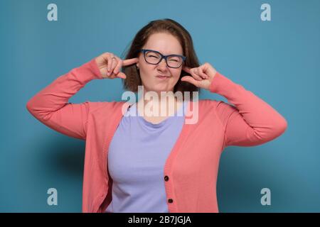 Smetta di fare questo suono fastidioso. Infelice stressò la giovane donna che tappava le orecchie con le dita, irritata dal forte rumore proveniente dai vicini Foto Stock