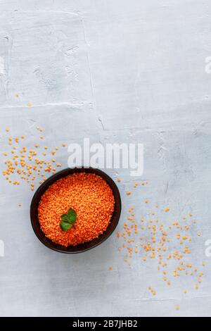 Lenticchie rosse in piastra nera su sfondo grigio chiaro. Foto Stock