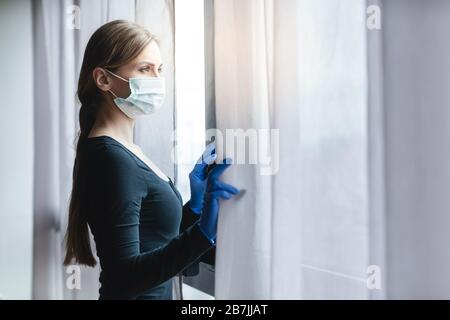 Annoiato donna in quarantena corona guardando fuori dalla finestra Foto Stock