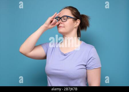 Calma bella donna che pratica hatha yoga nadi shodhana pranayama o alternare nostril respirazione. Studio girato su una parete blu. Foto Stock