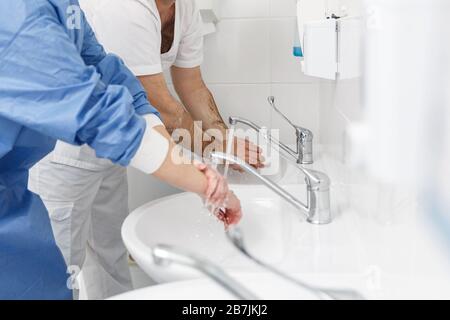 Medici che lavano le mani utilizzando liquidi disinfettanti in una clinica chirurgica. Concetto di sanità e medicina Foto Stock