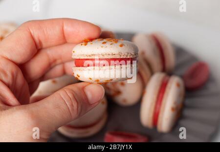 La mano tiene un macaron di fragole Foto Stock