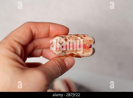 La mano tiene un macaron di fragole Foto Stock