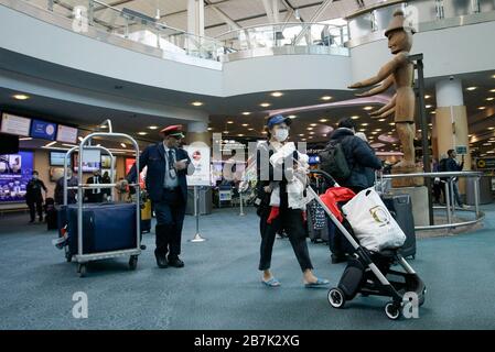Vancouver, Canada. 16 Marzo 2020. Un viaggiatore che indossa la maschera facciale arriva all'Aeroporto Internazionale di Vancouver a Richmond, Canada, il 16 marzo 2020. Il primo ministro canadese Justin Trudeau ha annunciato una serie di nuove misure il lunedì pomeriggio per contenere ulteriormente la diffusione del COVID-19 in Canada. Credit: Liang Sen/Xinhua/Alamy Live News Foto Stock