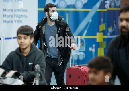 Vancouver, Canada. 16 Marzo 2020. Un viaggiatore che indossa la maschera facciale arriva all'Aeroporto Internazionale di Vancouver a Richmond, Canada, il 16 marzo 2020. Il primo ministro canadese Justin Trudeau ha annunciato una serie di nuove misure il lunedì pomeriggio per contenere ulteriormente la diffusione del COVID-19 in Canada. Credit: Liang Sen/Xinhua/Alamy Live News Foto Stock