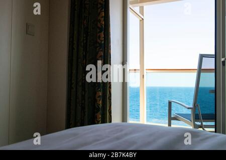 Vista su una sedia da patio vuota e balcone della nave da crociera o della camera per le vacanze, con vista sull'acqua blu dell'oceano Foto Stock