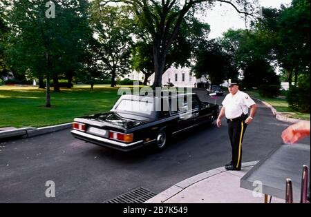 Washington, DC. USA, giugno 17 1992 Limousine ufficiale con il presidente russo Boris Yeltsin nella parte posteriore del sedile passa davanti ad un funzionario di servizio segreto di divisione in uniforme all'ingresso del cancello del Nord Ovest della Casa Bianca sulla sua strada per il portico del Nord per un'altra giornata di incontri al vertice con il presidente degli Stati Uniti George H.W. Boccola Foto Stock