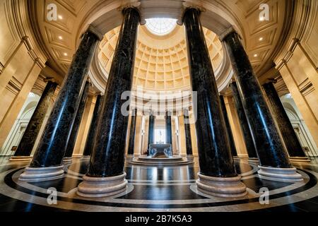 WASHINGTON, DC, Stati Uniti: La grande rotunda della National Gallery of Art di Washington, DC, mostra l'architettura neoclassica con la sua imponente cupola, il lucernario e le colonne corinzie. Una fontana centrale aggiunge un elemento dinamico allo spazio circolare, che funge da ingresso principale e punto focale del museo. Il design della rotonda, caratterizzato da un layout simmetrico e proporzioni classiche, esemplifica la visione dell'architetto John Russell Pope. Foto Stock