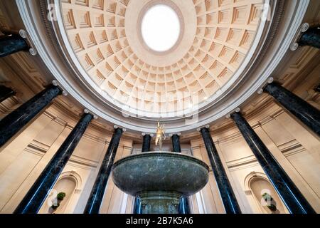 WASHINGTON, DC, Stati Uniti: La grande rotunda della National Gallery of Art di Washington, DC, mostra l'architettura neoclassica con la sua imponente cupola, il lucernario e le colonne corinzie. Una fontana centrale aggiunge un elemento dinamico allo spazio circolare, che funge da ingresso principale e punto focale del museo. Il design della rotonda, caratterizzato da un layout simmetrico e proporzioni classiche, esemplifica la visione dell'architetto John Russell Pope. Foto Stock