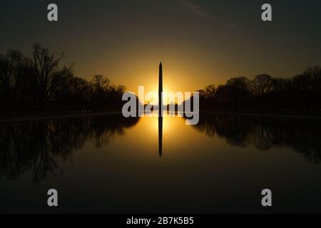 WASHINGTON DC, Stati Uniti: Il monumento a Washington si riflette nelle acque calme della piscina riflettente all'alba. La luce del mattino presto inonda il National Mall di un caldo bagliore, evidenziando l'iconico obelisco e creando una scena serena e pittoresca. Il Washington Monument, uno dei monumenti più riconoscibili degli Stati Uniti, è un tributo al primo presidente della nazione, George Washington. Foto Stock