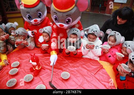 I bambini che indossano i copricapo del mouse si allineano per il porridge del riso per abbracciare il nuovo anno al Tempio di Xuanzang il giorno di Laba nella città di Nanjing, pr Jiangsu della Cina orientale Foto Stock