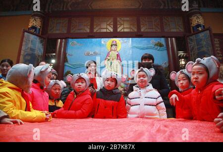 I bambini che indossano i copricapo del mouse si allineano per il porridge del riso per abbracciare il nuovo anno al Tempio di Xuanzang il giorno di Laba nella città di Nanjing, pr Jiangsu della Cina orientale Foto Stock