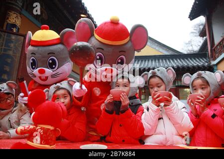 I bambini che indossano i copricapo del mouse si allineano per il porridge del riso per abbracciare il nuovo anno al Tempio di Xuanzang il giorno di Laba nella città di Nanjing, pr Jiangsu della Cina orientale Foto Stock