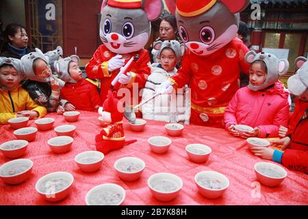 I bambini che indossano i copricapo del mouse si allineano per il porridge del riso per abbracciare il nuovo anno al Tempio di Xuanzang il giorno di Laba nella città di Nanjing, pr Jiangsu della Cina orientale Foto Stock