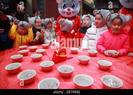 I bambini che indossano i copricapo del mouse si allineano per il porridge del riso per abbracciare il nuovo anno al Tempio di Xuanzang il giorno di Laba nella città di Nanjing, pr Jiangsu della Cina orientale Foto Stock