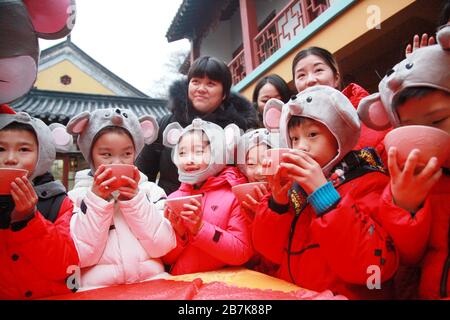 I bambini che indossano i copricapo del mouse si allineano per il porridge del riso per abbracciare il nuovo anno al Tempio di Xuanzang il giorno di Laba nella città di Nanjing, pr Jiangsu della Cina orientale Foto Stock