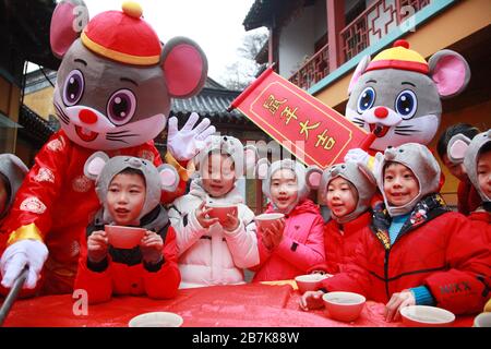 I bambini che indossano i copricapo del mouse si allineano per il porridge del riso per abbracciare il nuovo anno al Tempio di Xuanzang il giorno di Laba nella città di Nanjing, pr Jiangsu della Cina orientale Foto Stock