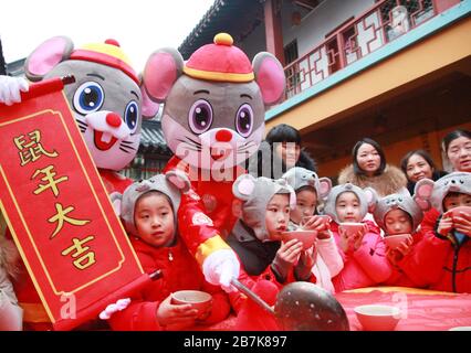 I bambini che indossano i copricapo del mouse si allineano per il porridge del riso per abbracciare il nuovo anno al Tempio di Xuanzang il giorno di Laba nella città di Nanjing, pr Jiangsu della Cina orientale Foto Stock