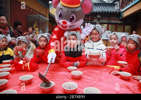 I bambini che indossano i copricapo del mouse si allineano per il porridge del riso per abbracciare il nuovo anno al Tempio di Xuanzang il giorno di Laba nella città di Nanjing, pr Jiangsu della Cina orientale Foto Stock