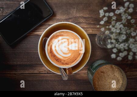 Immagine top down di un latte e cellulare che mostra la cultura del caffè o lo stile di vita del fine settimana dei Millennial Foto Stock