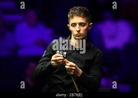 Il giocatore di snooker inglese Joe o'Connor getta il suo culo mentre considera un colpo contro il giocatore di snooker professionista scozzese John Higgins alla prima rou Foto Stock