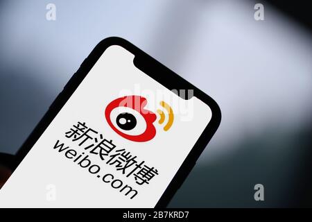 Foto creativa: Il logo di Sina Weibo, un sito web cinese di microblogging (weibo) simile a Twitter, è mostrato su uno smartphone come il proprietario lo sta utilizzando, Foto Stock