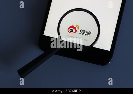 Foto creativa: Il logo di Sina Weibo, un sito web cinese di microblogging (weibo) simile a Twitter, è mostrato su uno smartphone come il proprietario lo sta utilizzando, Foto Stock