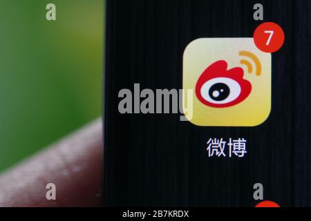 Foto creativa: Il logo di Sina Weibo, un sito web cinese di microblogging (weibo) simile a Twitter, è mostrato su uno smartphone come il proprietario lo sta utilizzando, Foto Stock