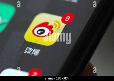 Foto creativa: Il logo di Sina Weibo, un sito web cinese di microblogging (weibo) simile a Twitter, è mostrato su uno smartphone come il proprietario lo sta utilizzando, Foto Stock