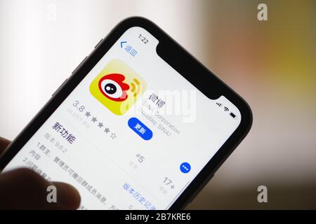 Foto creativa: Il logo di Sina Weibo, un sito web cinese di microblogging (weibo) simile a Twitter, è mostrato su uno smartphone come il proprietario lo sta utilizzando, Foto Stock