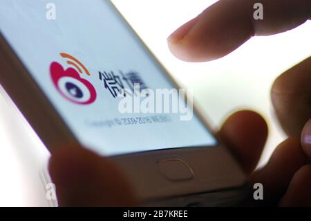 Foto creativa: Il logo di Sina Weibo, un sito web cinese di microblogging (weibo) simile a Twitter, è mostrato su uno smartphone come il proprietario lo sta utilizzando, Foto Stock