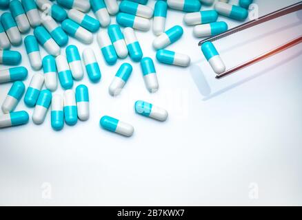 Forcipe prelevare la capsula bianco-blu dal gruppo di pillole. Farmaci scegliere. Selezione di farmaci antibiotici. Concetto di resistenza ai farmaci antibiotici. QA e QC Foto Stock