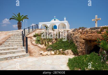 La piccola vecchia chiesa catacomba di San Thekla (Agia Thekla) e la bella nuova sulla sporgenza rocciosa che sale le scale. Ayia Napa. Cipro Foto Stock