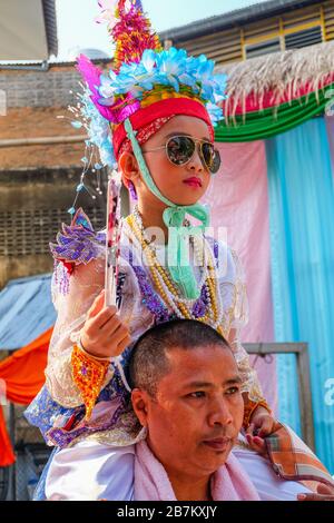 Chiang mai, Thailandia - 5 aprile 2018. POY Sang Long, una cerimonia annuale di ordinazione shan. Il ragazzo che indossa gli occhiali da sole siede sulle spalle del padre. Foto Stock