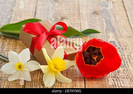 Fiori di tulipano e naffodils con scatola regalo su vecchie tavole di legno. Foto Stock
