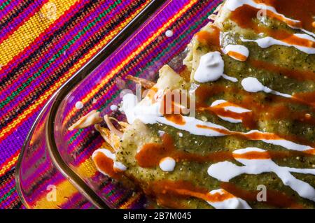 Enchiladas Verdes, o enchiladas verde, tortillas ripieno di pollo e condito con salsa verde, formaggio e crema Foto Stock