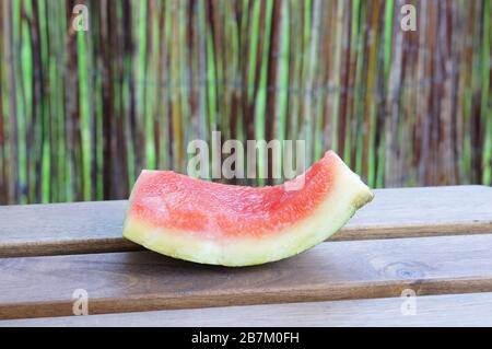 Pezzo di anguria mangiato su una superficie di legno con un sfondo sfocato Foto Stock