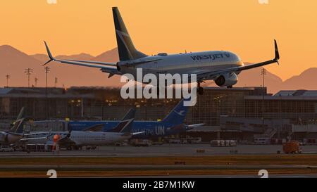 Richmond, British Columbia, Canada. 16 Marzo 2020. Un jet WestJet Airlines Boeing 737-800 atterra al tramonto, all'Aeroporto Internazionale di Vancouver, Richmond, B.C., Canada, lunedì 16 marzo 2020. All'inizio del giorno il governo canadese, nel tentativo di fermare la diffusione del romanzo coronavirus, ha annunciato che i confini della nazione sarebbero stati chiusi a partire da mercoledì 18 marzo a tutti i viaggiatori diversi dai cittadini canadesi e residenti permanenti, cittadini statunitensi, diplomatici e lavoratori essenziali. Credit: Bayne Stanley/ZUMA Wire/Alamy Live News Foto Stock