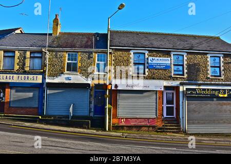 Una fila di piccoli negozi tradizionali, alcuni con appartamenti sopra, sul lato della strada principale attraverso la città. Negozi con servizio navetta la domenica, Foto Stock