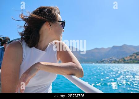 Bella donna matura ama il viaggio estivo in mare, femmina sul lato di una piccola barca da diporto. Mar Mediterraneo, Baia di Mirabello, isole greche all'orizzonte. Clea Foto Stock