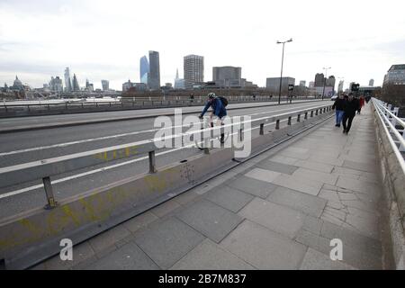 Un pendolari attraversa un Waterloo Bridge vuoto a Londra, il giorno dopo che il primo ministro Boris Johnson ha invitato le persone a stare lontano da pub, club e teatri, lavorare da casa se possibile ed evitare tutti i contatti non essenziali e viaggiare per ridurre l'impatto della pandemia di coronavirus. Foto Stock