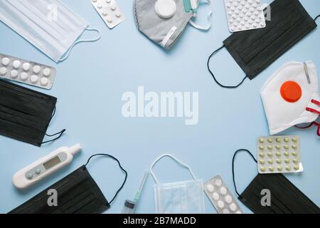 Diversi tipi di maschera facciale protettiva medica, pillole, termometro su blu. Vista dall'alto. Prevenzione dei virus. Spazio per il testo. Foto Stock