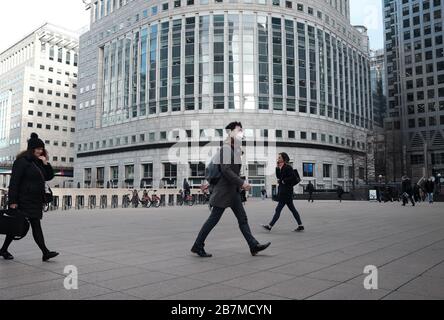 Un uomo che indossa una maschera attraversa Reuters Plaza a Canary Wharf, Londra, il giorno dopo che il primo ministro Boris Johnson ha invitato le persone a stare lontano da pub, club e teatri, lavorare da casa se possibile ed evitare tutti i contatti non essenziali e viaggiare per ridurre l'impatto della pandemia di coronavirus. Foto Stock