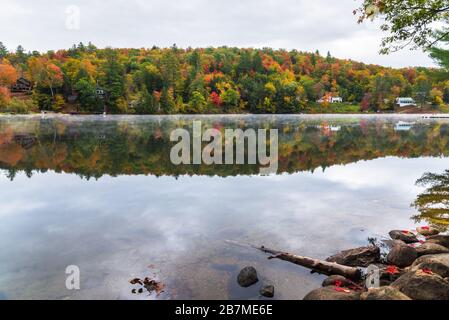 Lago di montagna con case vacanza sulla riva boscosa durante la stagione di colore autunno Foto Stock