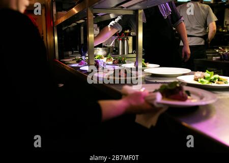 Chef che aggiunge alcune verdure su un pezzo di carne durante la sua preparazione Foto Stock