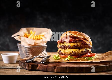 Set di hamburger e patatine fritte. Un set standard di bevande e cibo nel pub, birra e spuntini. Sfondo scuro, fast food. Foo americano tradizionale Foto Stock